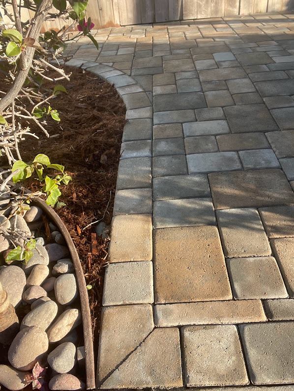 Detail of curved paver edge with river rock border along a planting bed