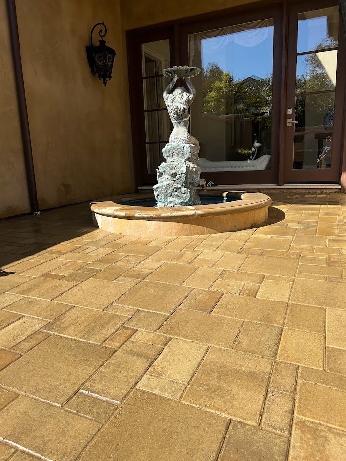 Stone fountain feature framed by the new paver courtyard
