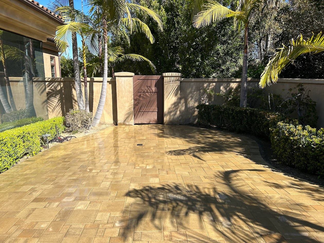 Paver courtyard leading to a side gate framed by palm trees
